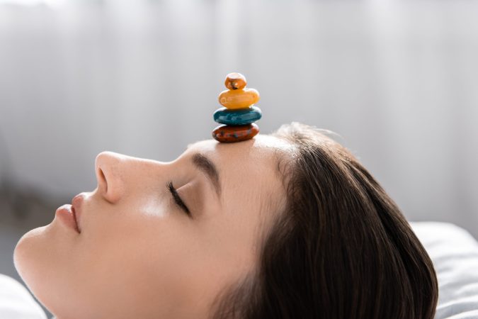 woman-lying-with-closed-eyes-with-colorful-stones-2024-11-17-07-25-23-utc
